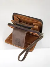 Mini billetera de cuero con diseño combinado de cuero liso marrón y cuero con pelo vacuno estampado. Cuenta con cierre de solapa con broche magnético y logo de búho grabado, además de una correa de muñeca extraíble.