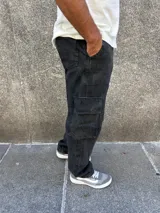 Pantalón cargo baggy negro gastado, con bolsillos laterales y un bolsillo tipo cargo en cada pierna.