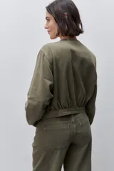 Campera azul marino de algodón, de corte relajado y largo corto, con cuello redondo, cierre frontal con botones metálicos, bolsillos delanteros y mangas largas con puños ajustables.