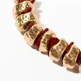 Collar corto con cuentas de piedra color borgoña y piezas de metal dorado con textura irregular.