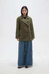 Chaqueta de corte holgado en color negro, con cuello solapa, cierre frontal con botones y bolsillos laterales.