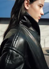 Chaqueta de estilo bomber color negro, confeccionada en 100% piel ovino con acabado de napa y diseño oversize. Cuenta con cuello alto envolvente, manga larga con puños ajustables, cierre delantero oculto con botón magnético y forro interior de poliéster.