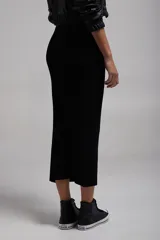 Pollera midi negra de tejido de punto, corte ajustado y largo hasta la pantorrilla.