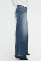 Jean de tiro alto en denim de algodón con leve stretch. Presenta piernas amplias, corte holgado, bolsillos tipo parche en la parte frontal y raya marcada a lo largo de las piernas. Incluye cierre y botón metálico.