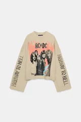 Sudadera beige de mezcla de algodón, con cuello redondo, manga larga y bajo deshilachado. Presenta un estampado frontal de la banda AC/DC con llamas naranjas y el texto "Highway to Hell" en las mangas.
