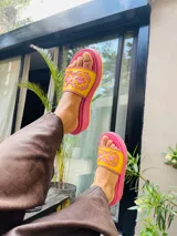 Sandalias tipo chinelas de cuero color suela, con plataforma baja y diseño de capellada con calados geométricos inspirados en motivos pampeanos.