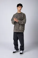 Buzo de cuello redondo con efecto de teñido artesanal acid wash. Presenta un corte oversize, mangas largas con puños acanalados y etiqueta pequeña en el puño izquierdo.