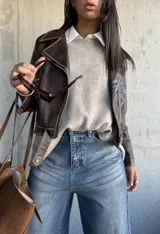 Chaqueta estilo biker de cuero vegano en color chocolate, con cierre frontal asimétrico, solapas clásicas y detalles de costuras visibles.