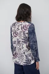 Blusa de manga larga con estampado floral en tonos azul marino y crema. Presenta un escote en V con tapeta abotonada en contraste y un corte holgado.