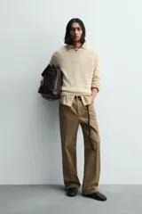 Jersey de punto color beige claro, con textura irregular y cuello redondo. Presenta un calce relajado y manga larga con puños y ruedo en rib.