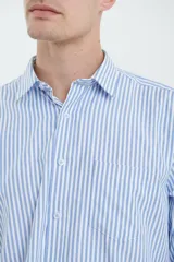 Camisa celeste y blanca a rayas verticales, de manga larga con puños abotonados y cuello clásico.