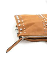 Cartera bandolera marrón decorada con tachas metálicas plateadas en los laterales y en dos líneas verticales frontales, con correa ajustable y cierre superior.