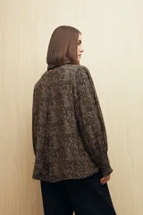 Camisa blanca con estampado lineal irregular en negro, de calce relajado, cuello clásico, abotonadura frontal y mangas largas con puños elastizados.