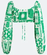 Blusa cropped blanca con estampado de motivos verdes, escote corazón con lazo, mangas largas abullonadas y confeccionada en tricolina.