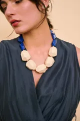 Collar de diseño llamativo compuesto por cuentas geométricas grandes, combinando piezas de madera en tono natural con cuentas facetadas en color azul.