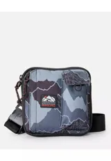 Morral Rip Curl con diseño de camuflaje en tonos gris y negro, de formato cuadrado, con múltiples bolsillos frontales, correa de hombro ajustable y parche con logo de la marca.