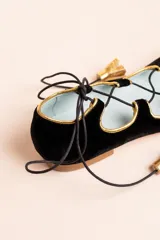 Bailarinas de terciopelo negro con ribete dorado y cordón negro. Interior de piel y suela de cuero. Cuentan con una cuña interna de 1,5 cm. Modelo exclusivo diseñado y fabricado en España.