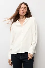 Camisa de corte clásico y calce holgado, con cuello camisero, cierre frontal de botones y mangas largas con puños abotonados.