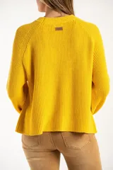 Sweater de punto en color amarillo, con diseño oversize, cuello redondo y manga larga. Presenta un pequeño bordado de un velero en la parte superior del pecho.
