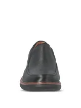 Zapato Hush Puppies modelo Oregon, color negro con diseño slip-on y elásticos laterales. Fabricado en cuero con costuras visibles y suela de goma EVA.