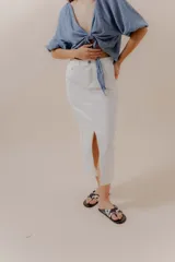 Falda midi de denim blanco, tiro alto, con abertura frontal pronunciada.