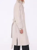 Tapado largo color beige con cuello solapa, cinturón y mangas largas con detalle matelassé.