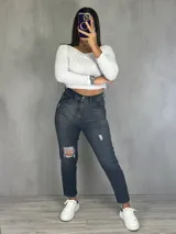 Pantalón de jean gris oscuro, corte mom, tiro alto, con roturas en las rodillas y tobillos.