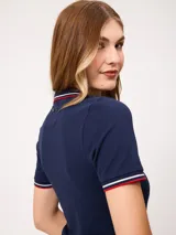 Remera polo azul marino de manga corta, con cuello en V sin botones y ribetes tricolores en el cuello y los puños.