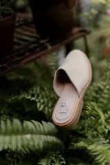 Mules de cuero negro con tachas plateadas en el borde de la suela y plantilla con logo estampado.