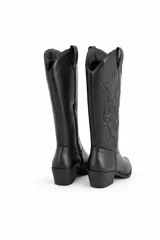 Botas estilo texanas de caña alta, color negro, con diseño de costuras decorativas en el empeine y en la caña. Cuentan con taco cuadrado y cierre lateral.