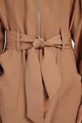 Mono largo color beige con cierre frontal, mangas abullonadas y cinturón con lazo.