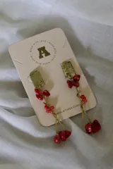 Aros colgantes con base de bronce color dorado y piedras rojas.