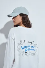 Remera de manga larga en color blanco, con corte relajado y cuello redondo. Presenta un pequeño estampado gráfico en la parte inferior frontal con la frase 'WHO WH WHO?' y un dibujo de un perro.