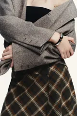 Pulsera rígida de metal plateado con diseño articulado y terminaciones con piedras incrustadas en tono marrón.