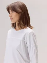 Remera de algodón con cuello redondo y manga larga. Presenta un diseño con costuras horizontales a la altura del pecho y costuras verticales en las mangas, brindando un detalle distintivo a la prenda.