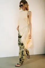 Top asimétrico de mezcla de lyocell en color amarillo claro, con cuello redondo y diseño fluido de corte irregular con una manga larga y un lateral drapeado.