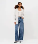 Pantalón de jean estilo wide leg con cintura media, cierre frontal con botón y cremallera, bolsillos funcionales y diseño de pierna amplia con recorte transversal.