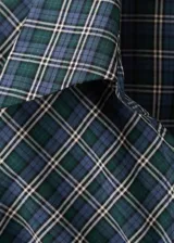 Blusa de algodón con diseño entallado y patrón de cuadros, cuello camisero, manga larga con puños abotonados y cierre frontal de ganchos con detalles fruncidos.