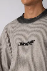 Sweater de punto acanalado con diseño degradado de negro a gris en el cuello y el ruedo. Presenta un corte regular y un pequeño bordado central en el pecho.