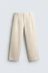 Pantalón relaxed fit color beige confeccionado en tejido de algodón con tacto suave, cintura con pliegues delanteros y cierre frontal con cremallera y botón.