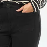 Pantalón negro de denim, corte flare, con bolsillos frontales tipo parche.