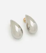 Par de aros tipo botón con forma de gota plateada y tornillo dorado contrastante.