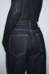 Jeans de tiro medio con corte baggy y pierna relajada. Presenta diseño de cinco bolsillos, cierre frontal con cremallera y botón, y bajo con vuelta marcada.