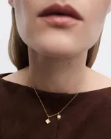 Aro colgante dorado con forma de dado y detalles de circonitas blancas.