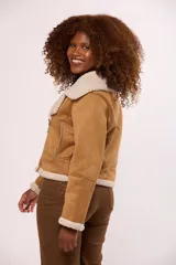 Campera tipo gamulán de color tostado con interior y solapas de corderito sintético en color crema. Presenta cierre frontal cruzado, mangas largas y bolsillos laterales.