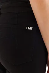 Pantalón color beige de corte recto, confeccionado en algodón y spandex. Presenta tiro medio y cierre frontal con botón y cremallera. Incluye cinturón marrón con hebilla plateada.