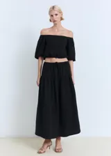 Blusa negra de diseño crop con escote palabra de honor, mangas cortas abullonadas y cintura elástica.