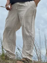 Pantalón de lino beige y crudo a rayas, de corte ancho y relajado.