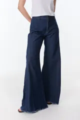 Pantalón de pierna ancha con acabado brillante, confeccionado en lino. Presenta un diseño de tiro medio con cierre de botón y cremallera, bolsillos traseros y etiqueta de marca en la cintura.
