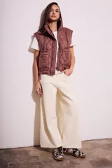 Chaleco acolchado color marrón con cierre frontal y bolsillos laterales.